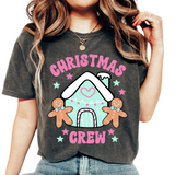 A woman wearing a Christmas Crew t-shirt with a colorful Christmas-themed graphic design, including a gingerbread man, a snowman, and festive decorations.