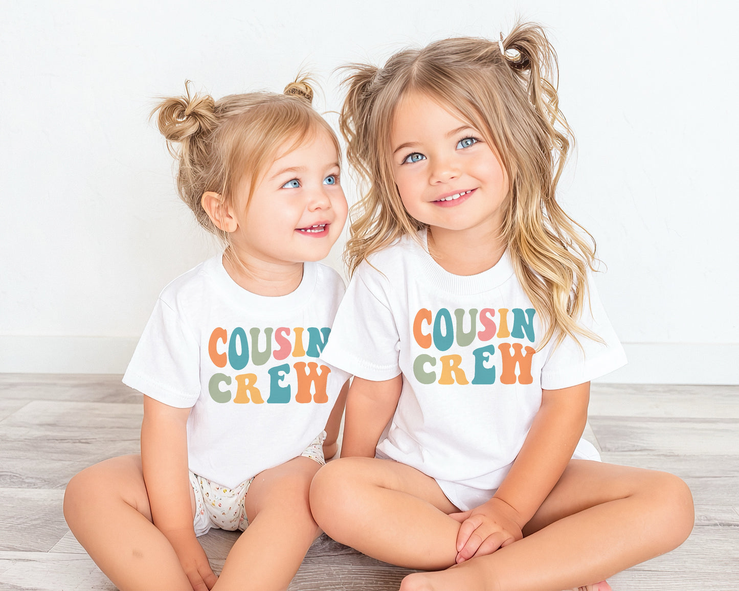 Two girls wearing a white shirt with a printed Cousin Crew design