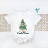 White crew neck Christmas tree shirt with text 'Feelin' Pine' printed on the front, displayed on a flat surface with a beige backdrop.