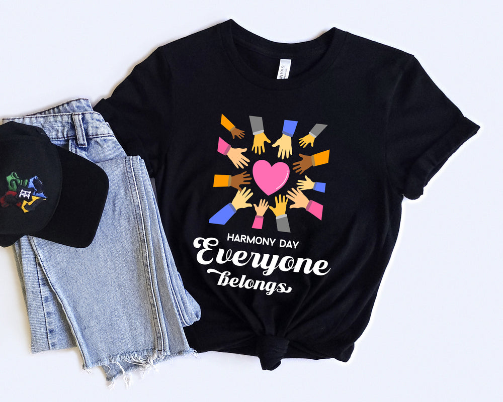 Black t-shirt with 'Harmony Day Everyone Belongs' design, black cap, and jeans on a white background