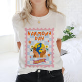 Person wearing a white t-shirt with 'Harmony Day Peace' design.