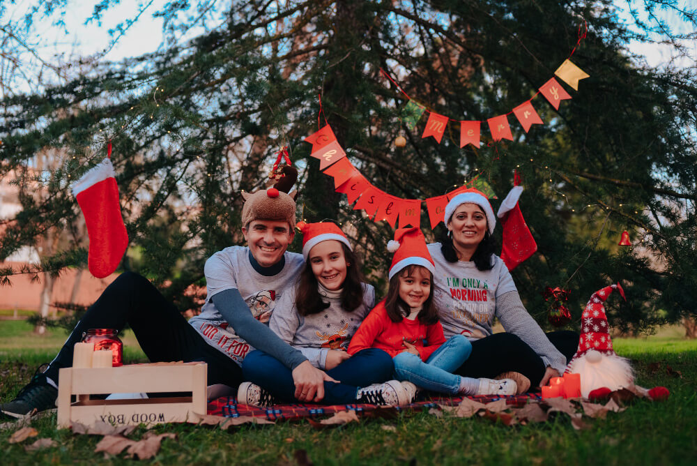 Australian family enjoying Christmas outdoors with festive shirts and a decorated Christmas tree