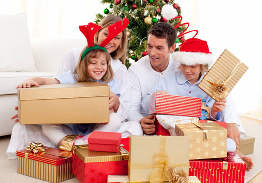 Family opening personalized Christmas gifts by the tree