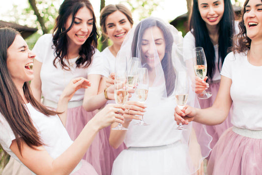 Women in matching Hen’s party shirts celebrating outdoors with festive decor and props.