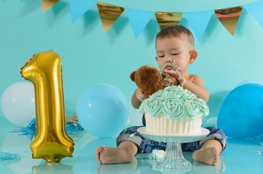 baby boy celebrating his first birthday with a cake 
