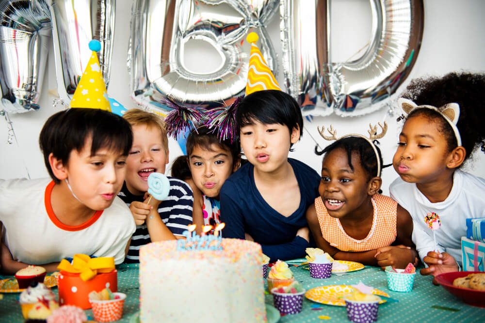 kids blowing the candles on a cake at a birthday party