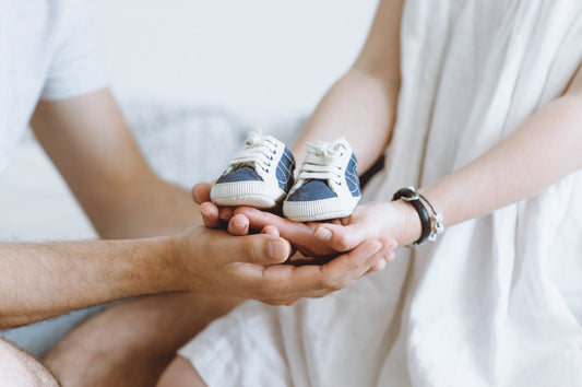 pregnancy reveal photo featuring mum and dad holding blue baby shoes