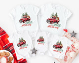 White t-shirts with red truck graphics and 'Jingle All the Way' text, surrounded by Christmas-themed items.