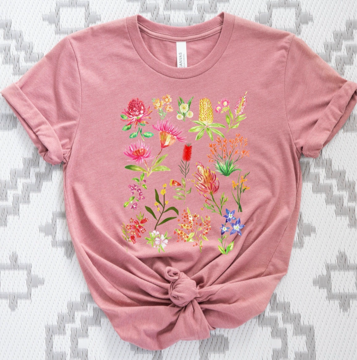 Pink t-shirt with colorful floral design on a textured gray background