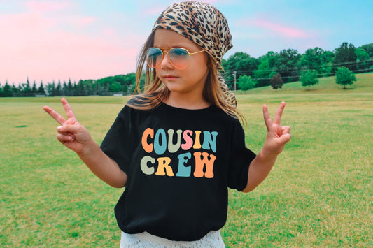 Girl wearing a black shirt with a cousin crew design printed on the shirt