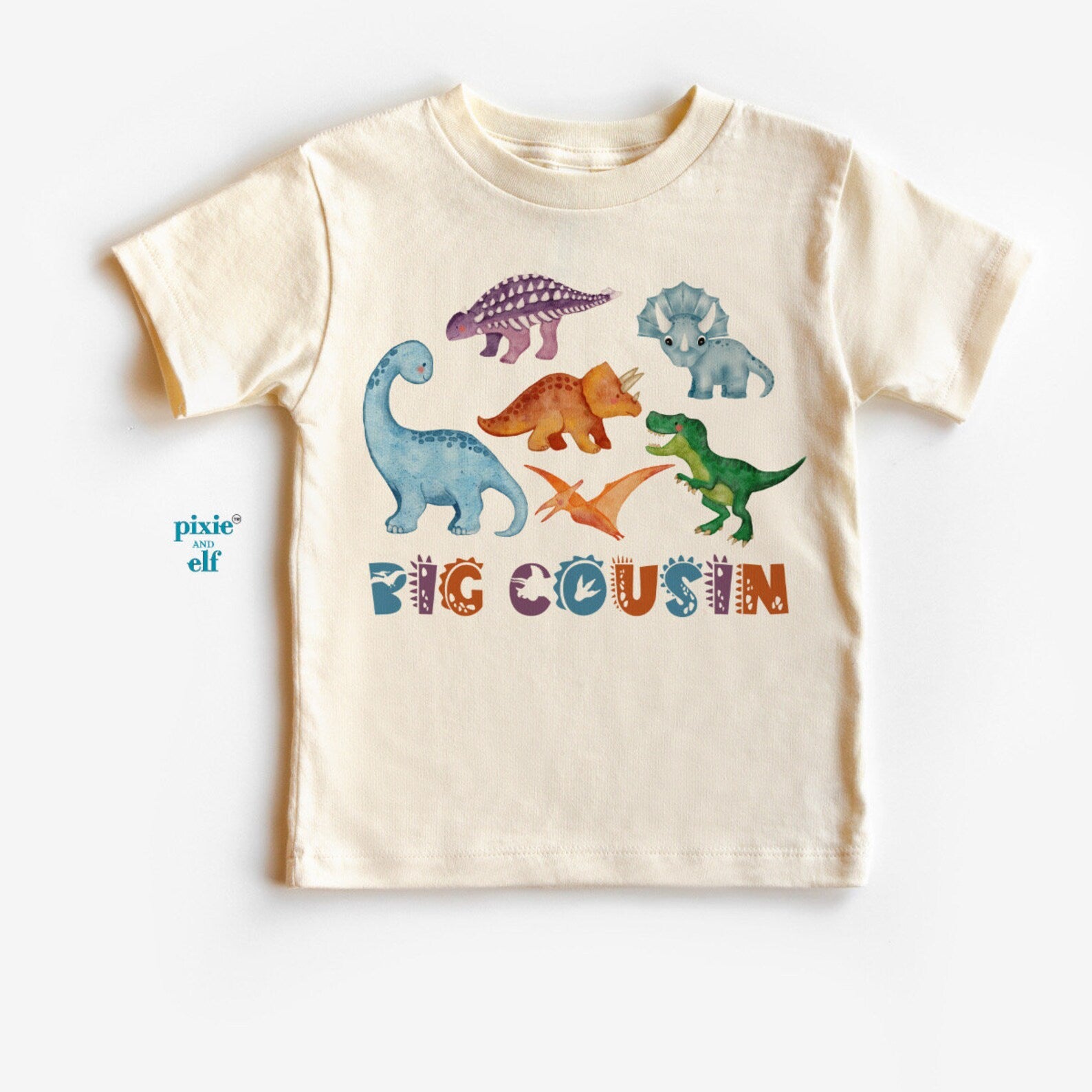 Beige t-shirt with colorful dinosaur graphics and 'BIG COUSIN' text on a white background