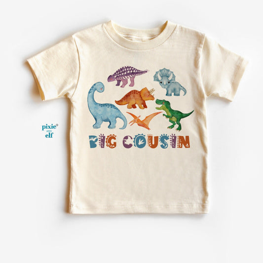 Beige t-shirt with colorful dinosaur graphics and 'BIG COUSIN' text on a white background