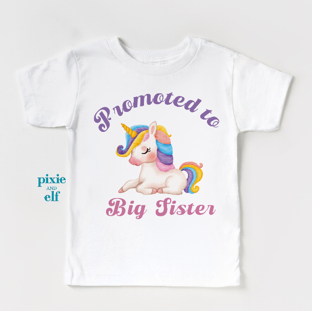 White t-shirt with a unicorn graphic and text 'Promoted to Big Sister' on a white background