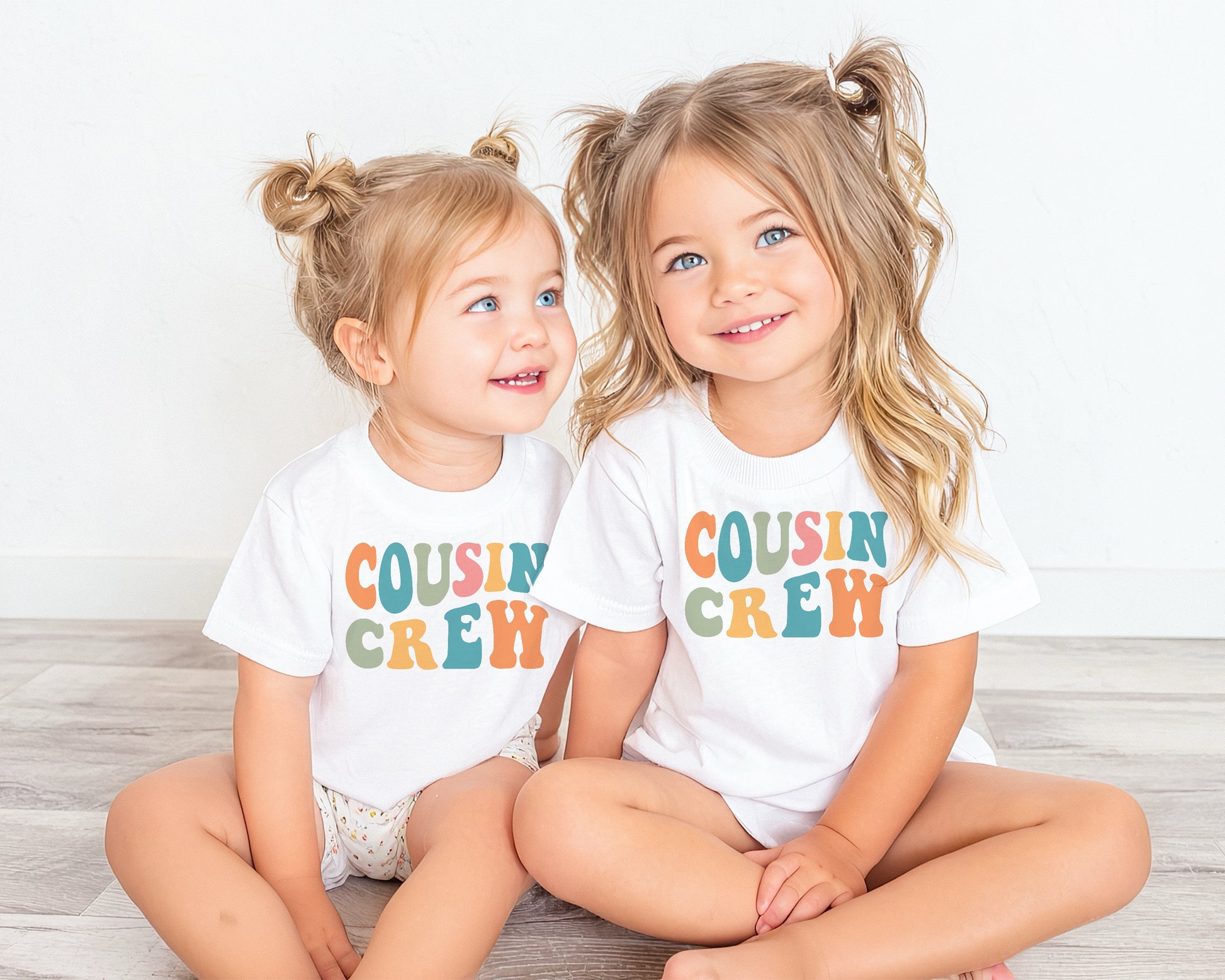 Two girls wearing a white shirt with a printed Cousin Crew design