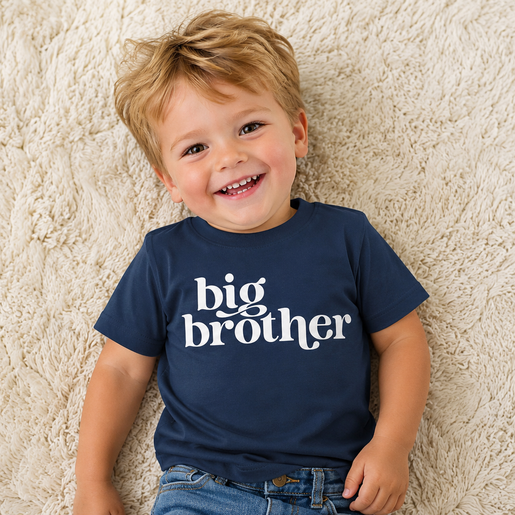 Child wearing a navy blue shirt with 'big brother' text on a beige carpet