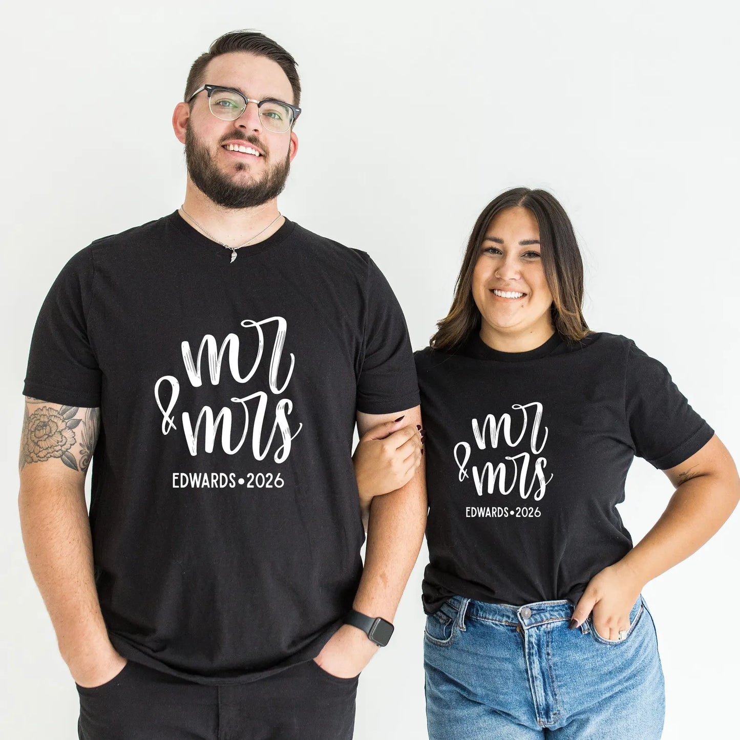 Two people wearing black t-shirts with 'Mr & Mrs Edwards 2026' text on a white background
