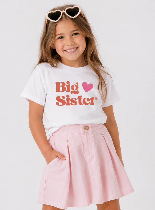 Child wearing a 'Big Sister' t-shirt with a pink skirt on a white background