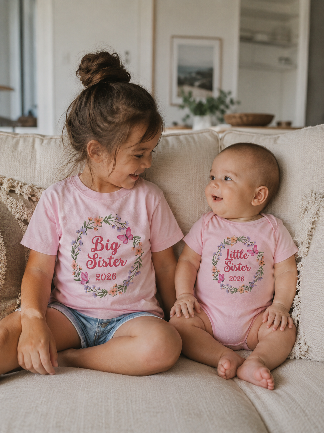 Two children sitting on a couch wearing matching shirts with floral text, in a home setting.