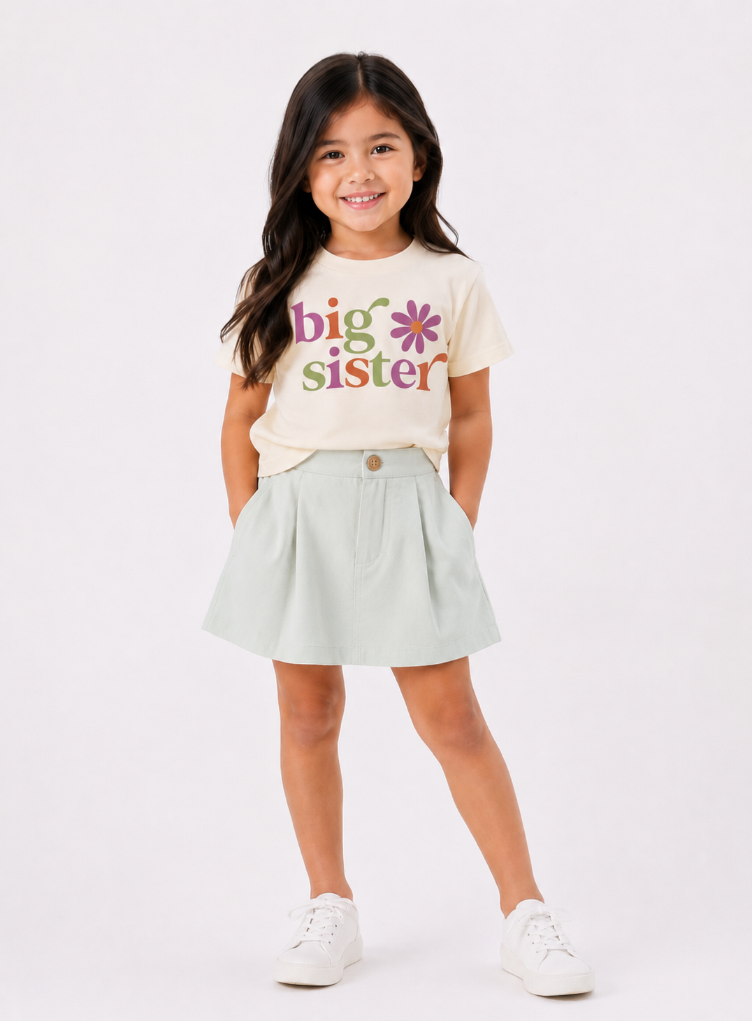 Young girl wearing a 'big sister' t-shirt with colorful text on a white background