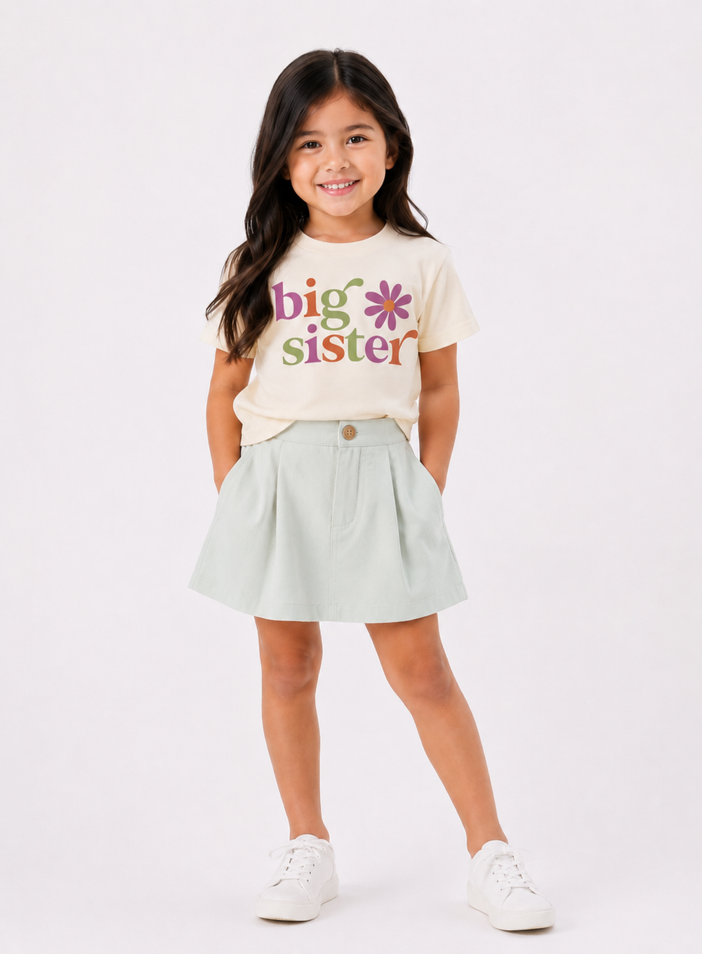 Young girl wearing a 'big sister' t-shirt with colorful text on a white background
