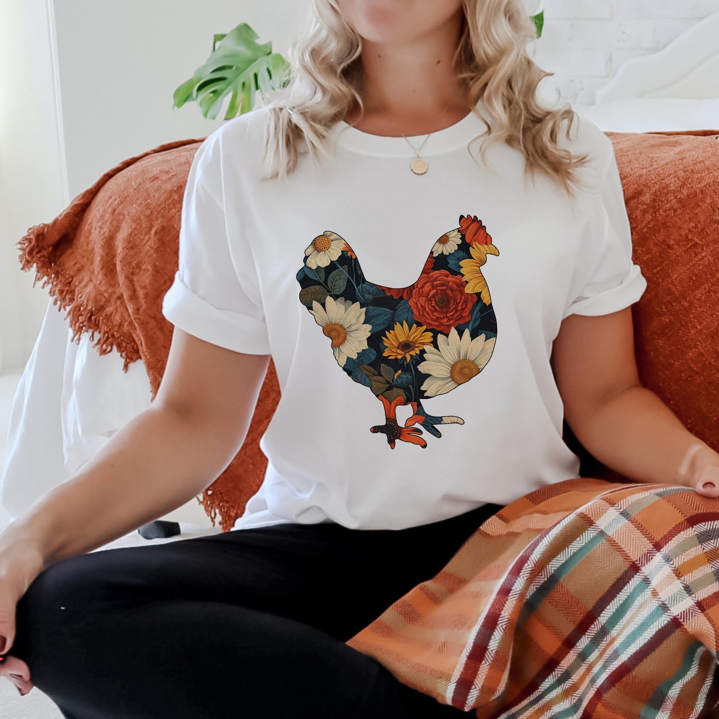 Person wearing a white t-shirt with a colorful rooster design sitting on a couch.