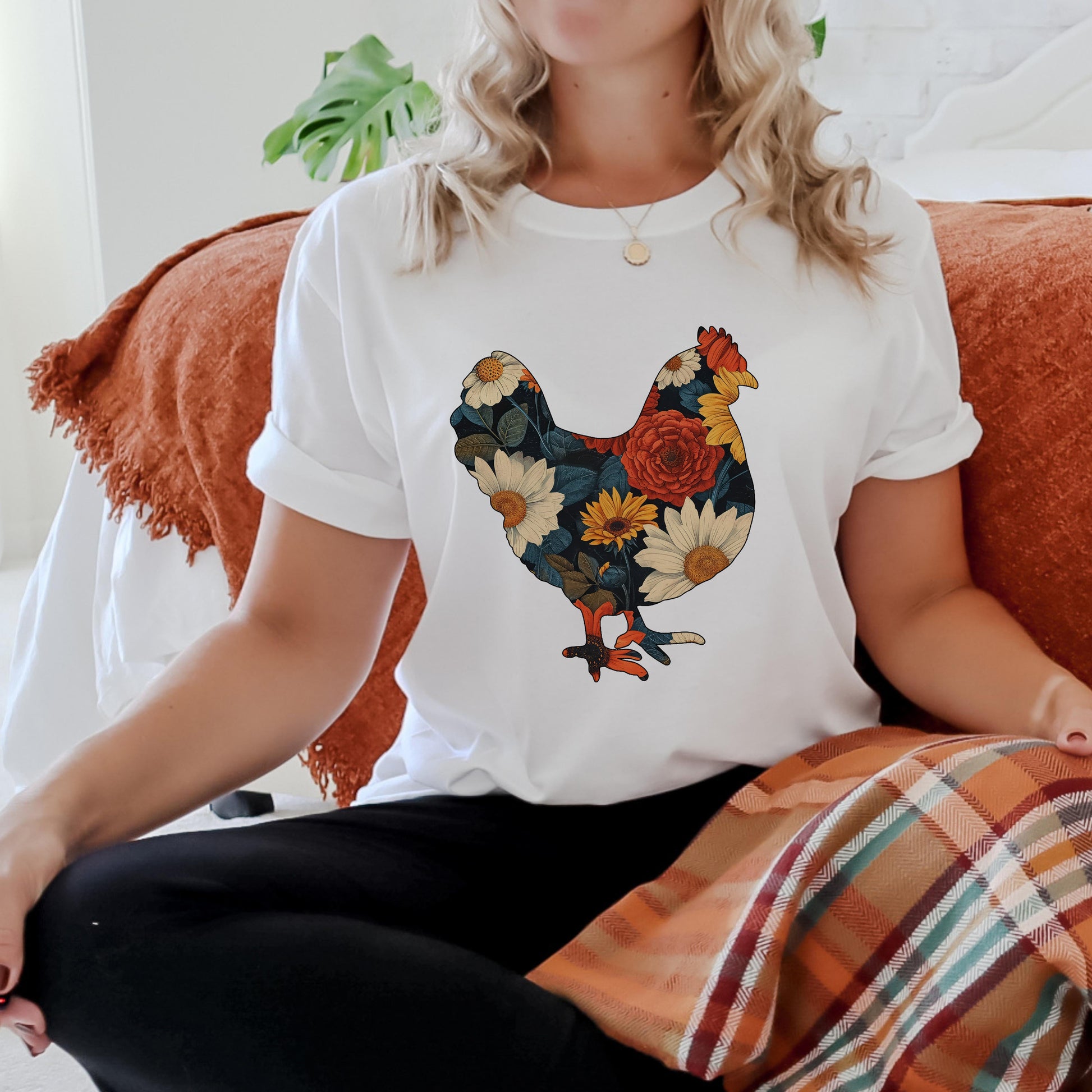Person wearing a white t-shirt with a colorful rooster design sitting on a couch.