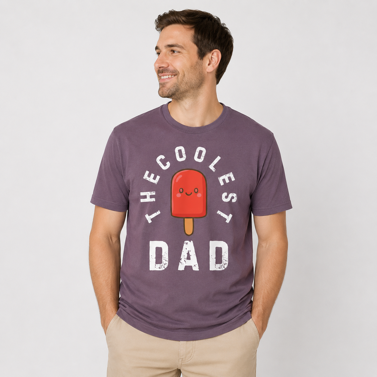 Man wearing a mauve t-shirt with a graphic and text 'The Coolest Dad" and an image of red popsicle on a plain background